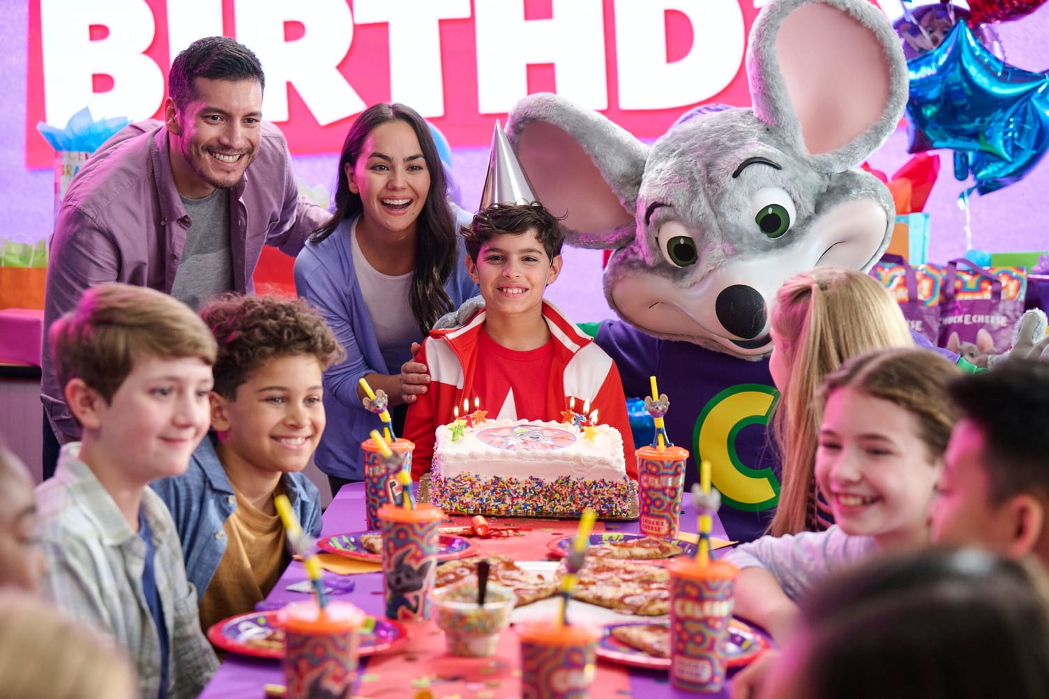 A group of partygoers and Chuck E. Cheese